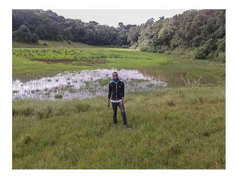 Alfred Mepukori standing near Ilturot natural water catchment area in Naimina Enkiyio Forest Alfred Mepukori standing near Ilturot natural water catchment area in Naimina Enkiyio Forest